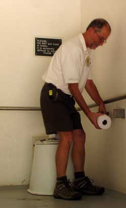 Dale adding rolls of toilet paper in a pit toilet room