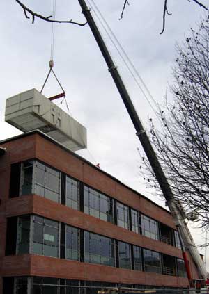 The heating and AC unit is hoisted to the roof