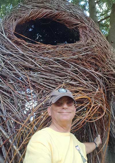 Standing next to a stick sculpture