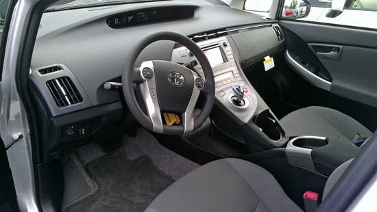 The cockpit of the Toyota Prius, Behind: Salesman, Cody, runs to the office for a license before a test drive. 