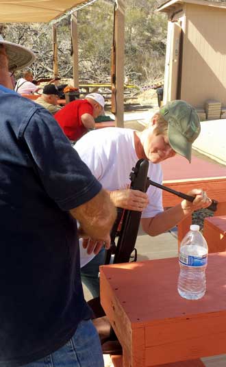 Gwen is loading her rifle, Behind: the target range