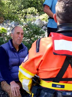 Swimmer Rice discusses the injury with John, Behind: a two person assist team attempts to move John toward the beach