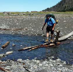 Richard crosses another creek then assists lane off the rocks to the beach