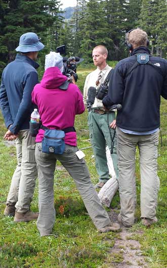 German film crew interviews Brad, the wilderness manager, Behind: we act our working part