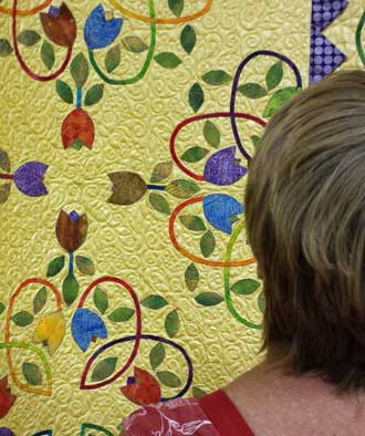 Gwen examines a quilt at the quilt show, Behind: Only Frank Lloyd Wright house in Oregon