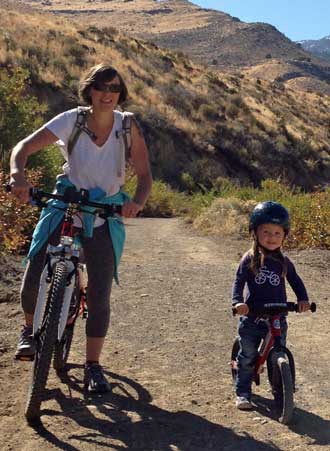 Mindy with Lucy riding her own bike. Behind is a group photo.