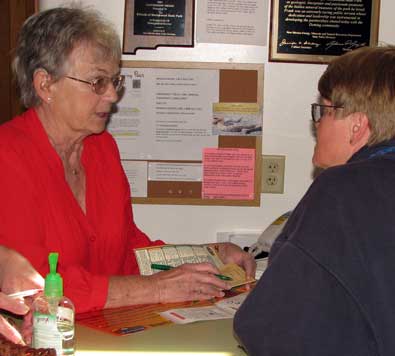 Marian is giving Gwen instructions of how to use the annual New Mexico State Park Pass