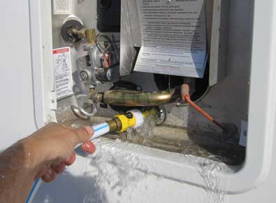 Using a wand to clear the debris from inside the tank