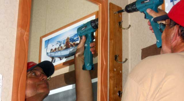 The  hat rack is mounted near the front door and next to the wall mirror.